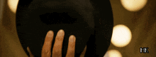 a close up of a person holding a hat with hk written on the bottom right