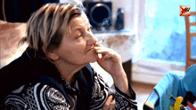 a woman is smoking a cigarette in front of a tv screen