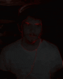 a man 's face is glowing in the dark and has red eyes