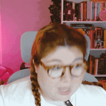 a woman wearing glasses is sitting in front of a bookshelf with a book titled ' a brief history '