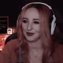 a woman with pink hair is wearing headphones and drinking from a cup .