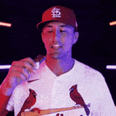 a man wearing a cardinals jersey holds a microphone