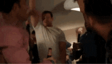 a group of men are standing around a table holding bottles of beer .