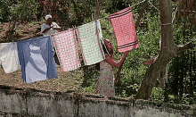 a woman hangs clothes on a clothes line in the woods