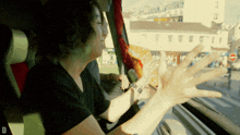 a woman in a black shirt is sitting in a car with her arms outstretched and the letter d on the bottom right