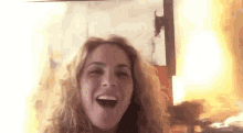 a woman with curly hair is laughing in front of a fire .