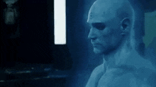 a man with a bald head is standing in front of a computer screen .