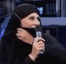 a woman wearing a hijab is holding a microphone .