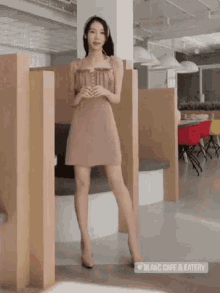 a woman in a brown dress and heels is standing in a restaurant .