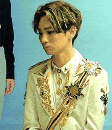 a young man with green hair is wearing a white suit with gold trim