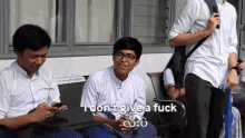 a group of young men are sitting on a bench and one of them says i don t give a fuck