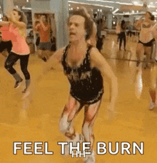 a group of people are dancing in a gym and the man is wearing a bodysuit .