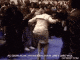 a woman is dancing in front of a crowd while a man in a suit stands behind her .