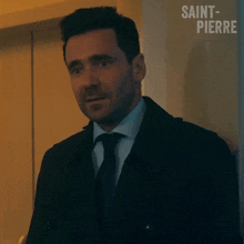 a man in a suit and tie says hi with his hand
