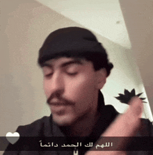 a man with a mustache is wearing a black hat and holding a flower