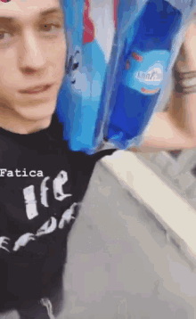a man wearing a shirt that says fatica is carrying a bottle of water