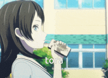 a girl drinking from a box that says tora