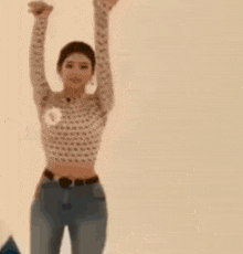 a woman in a crop top is dancing with her arms in the air .