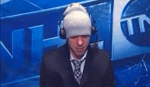 a man wearing a beanie and headphones is sitting in front of a blue wall .
