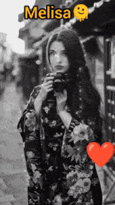 a black and white photo of a woman holding a camera with the name melisa on top