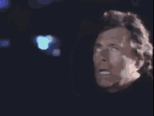a close up of a man 's face in a dark room with his mouth open .