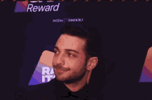 a man standing in front of a sign that says " reward "