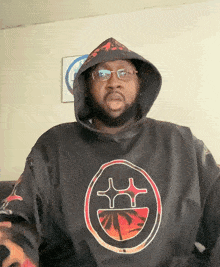 a man wearing glasses and a black hoodie with a smiley face on it