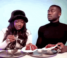 a man and a woman are sitting at a table eating cake with forks .