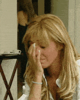 a woman wipes her face with her hand while wearing a bracelet
