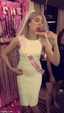 a bride in a white dress is eating a piece of pizza .