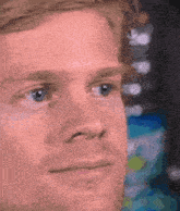 a close up of a man 's face with blue eyes looking at the camera .