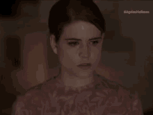 a close up of a woman 's face in a dark room wearing a pink shirt .