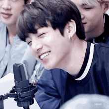 a young man is smiling in front of a microphone while wearing earrings