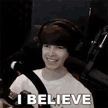 a young boy wearing headphones is smiling and says `` i believe '' .