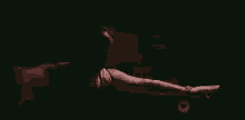 a man is laying on a bed in the dark with his arms outstretched .
