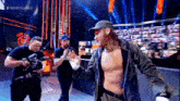 a man without a shirt is standing on a stage in front of a crowd while a cameraman records him
