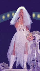 a woman in a bride 's dress sings into a microphone