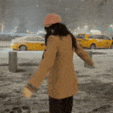 a woman wearing a pink hat is walking down a snow covered street