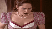 a woman wearing a pearl necklace and a floral top