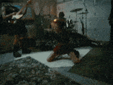 a woman is kneeling on the floor in front of a drum set while a man plays a guitar ..