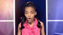 a little girl in a pink ruffled shirt is making a surprised expression