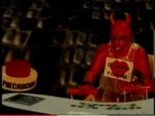 a man in a devil costume is standing in front of a yellow sign that says precaucion .