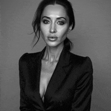 a black and white photo of a woman wearing a black jacket with a plunging neckline