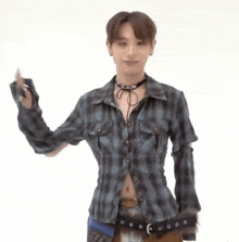 a young man wearing a plaid shirt and choker is waving his hand .
