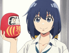 a girl with blue hair is holding a red doll with chinese characters on it
