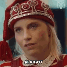 a woman wearing a santa hat and a sweater is making a face and saying alright .