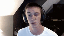 a young man wearing headphones looks at the camera with a serious look on his face