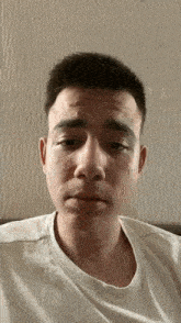 a young man in a white shirt is making a funny face