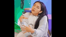 a woman with long black hair is making a funny face while sitting on a bed .