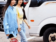 two women are walking in front of a white truck that says 1.2 ton